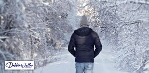 a man walking in a snowy woodland to illustrate an article on winter depression