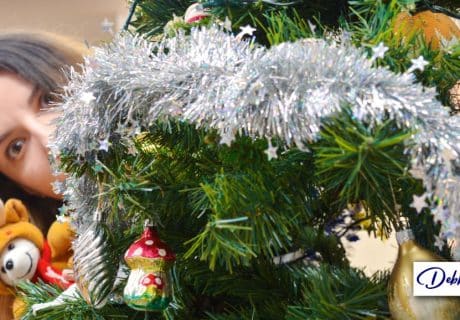 woman peering out from behind a christmas tree to illustrate an article on winter holiday stress