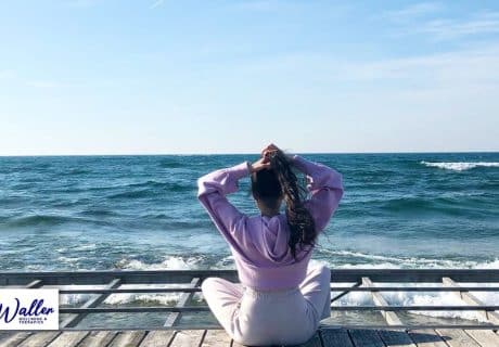 a woman taking deep breaths of clean air on the coast to illustrate an article about breathing exercises