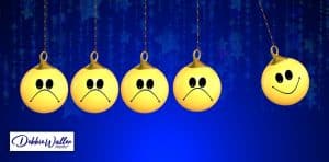 newton's cradle of balls with smiley faces, some looking negative and some positive to illustrate an article on breaking the cycle of negative thinking