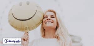 Laughing woman with smiley balloon to illustrate article on how to be happier