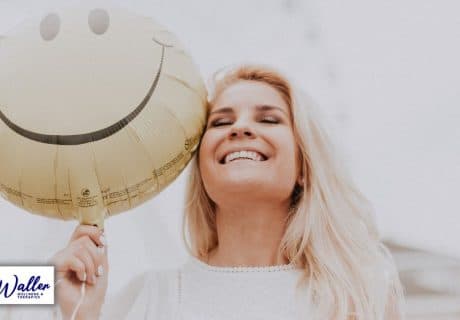 Laughing woman with smiley balloon to illustrate article on how to be happier