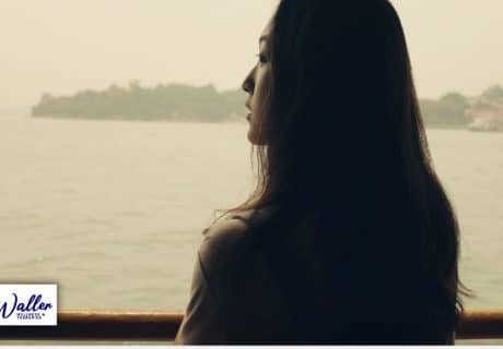 a woman alone staring through a window at a seascape to illustrate a article on loneliness