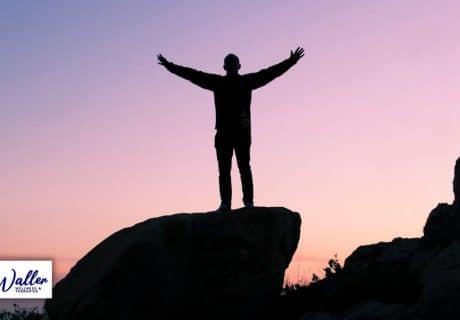 a person stood on a rock silhouetted against sunrise to illustrate an article on mind hacks to improve confidence