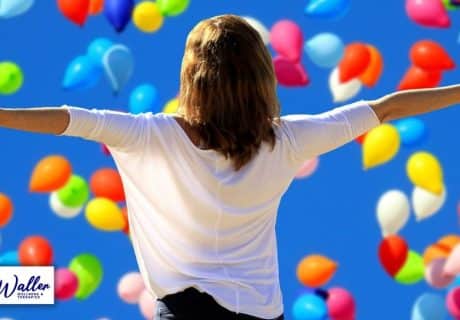 woman surrounded by balloons to illustrate article on breaking the habit of negative thinking