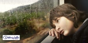 a child looking miserably through a window to illustrate an article about school anxiety