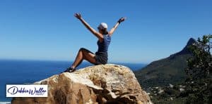 woman celebrating after rock climbing to illustrate an article on reaching goals