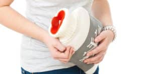 hypnotherapy for ibs irritable bowel syndrome woman clutching a hot water bottle to her stomach
