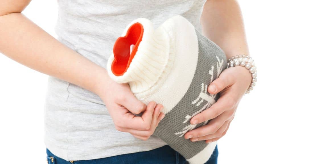 hypnotherapy for ibs irritable bowel syndrome woman clutching a hot water bottle to her stomach